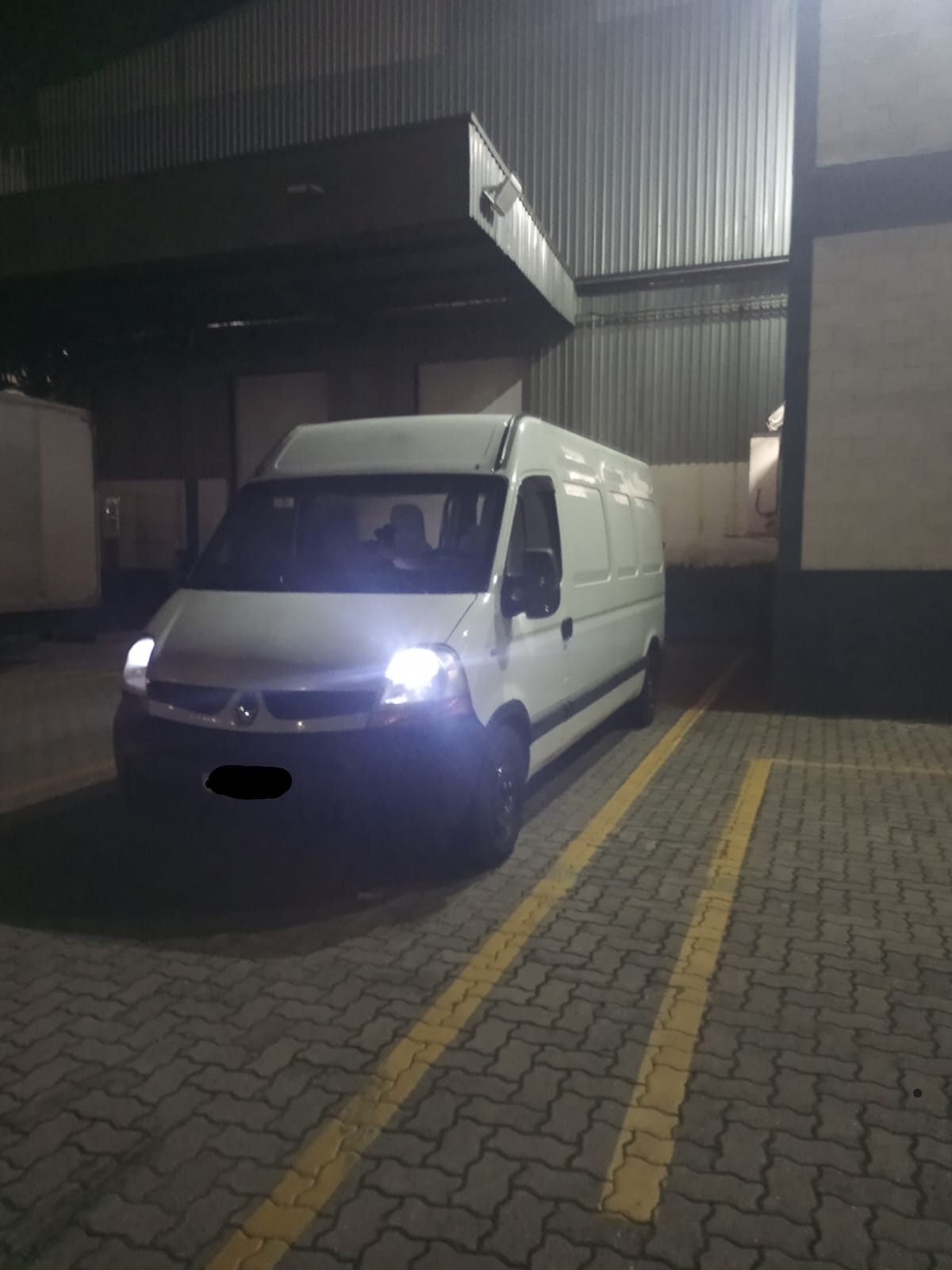 Van branca estacionada em frente a galpão